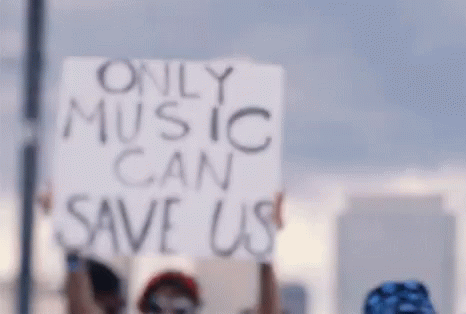 a woman holding a sign that says only music can save us