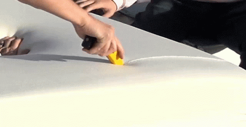 the man in black shirt is putting a sponge on a white car