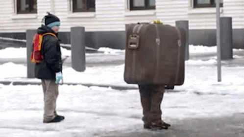 two people in the snow with luggage on their backs