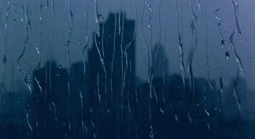 a city from inside a rain - soaked window