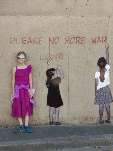 three women standing next to each other near a wall with writing on it