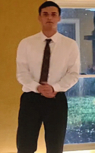 a man is standing wearing black slacks and a white shirt
