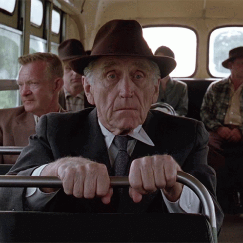 an older man with big eyes sitting in the back of a bus
