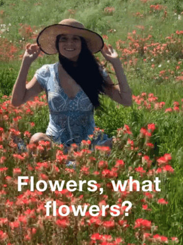 a girl with long hair wearing a hat and dress is kneeling in a field full of blue flowers
