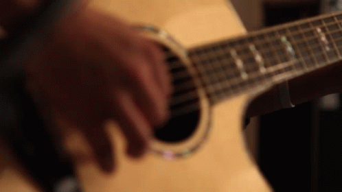 a close up s of someones fingers playing an acoustic guitar