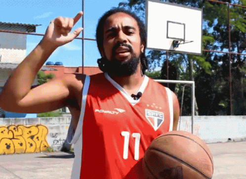 a man with a beard standing next to a basketball