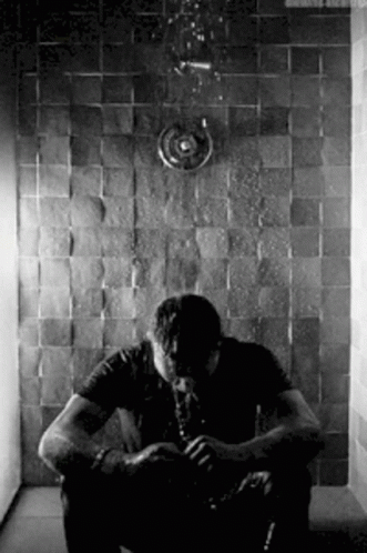 a man sits in the corner of a shower
