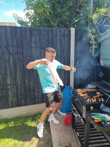 a man in yellow shirt cooking on a bbq