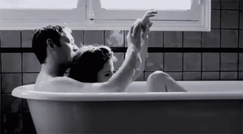 a black and white po of a man and woman sitting in a bathtub