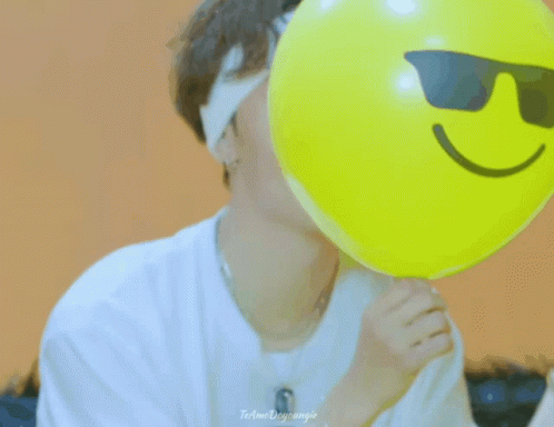the man is holding a balloon with a happy face