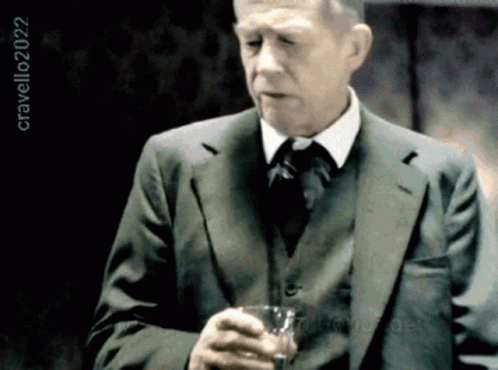 a man is in suit and tie holding a wine glass