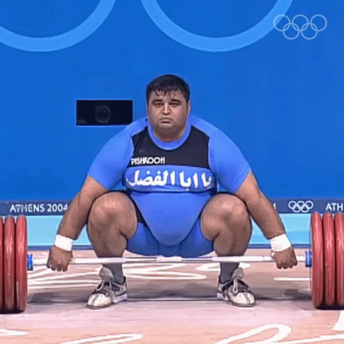 a man squatting down while holding a blue bar