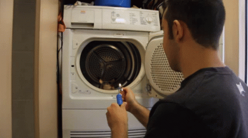 a man fixes the dryer in the wall