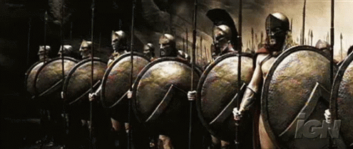 a group of people standing around near each other wearing shields and swords