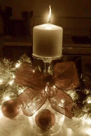 a lit candle with a christmas tree in the background