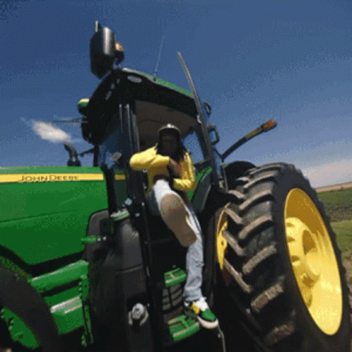 a farmer drives a green tractor on a hill