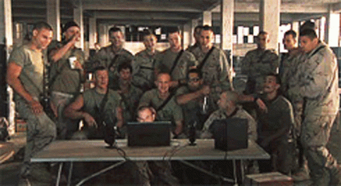 soldiers pose for a group po in front of laptops