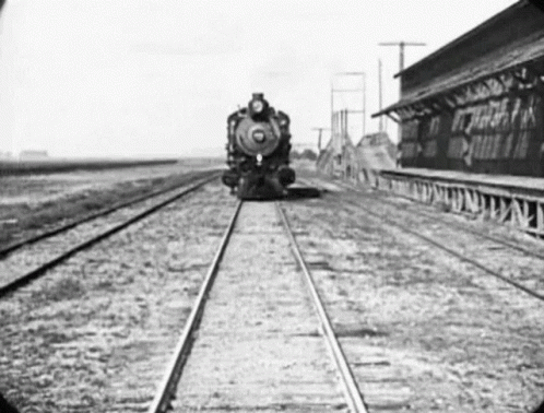 an old picture of a train coming down the tracks