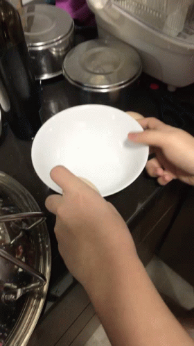 someone holding a plate near the stove and making food