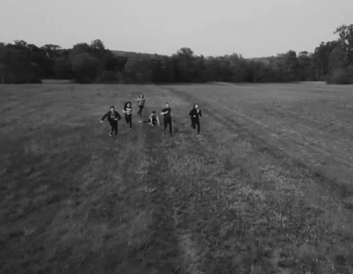 people in black and white running across an open field