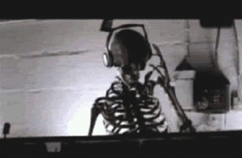 a skeleton sitting on top of a shelf with headphones