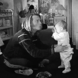 a man in black shirt holding a baby in living room