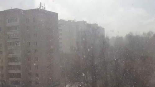 an apartment building next to a snowstorm that is falling down