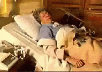 an elderly man lying in a bed with thermometer next to him