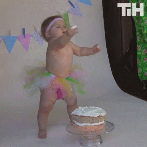 an infant is standing in front of a cake