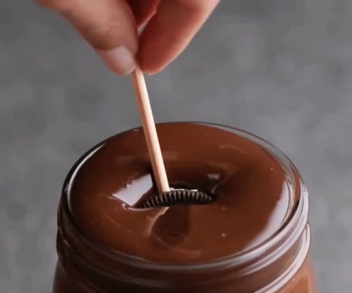 the person is using the toothbrush to put soing into the jar