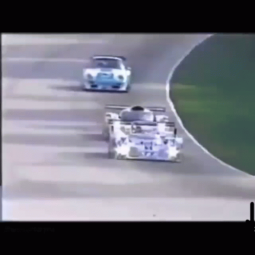 two vintage cars racing side by side on a race track
