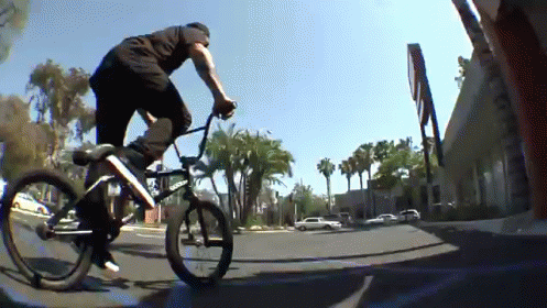 a man riding a bike down a street on top of a skateboard