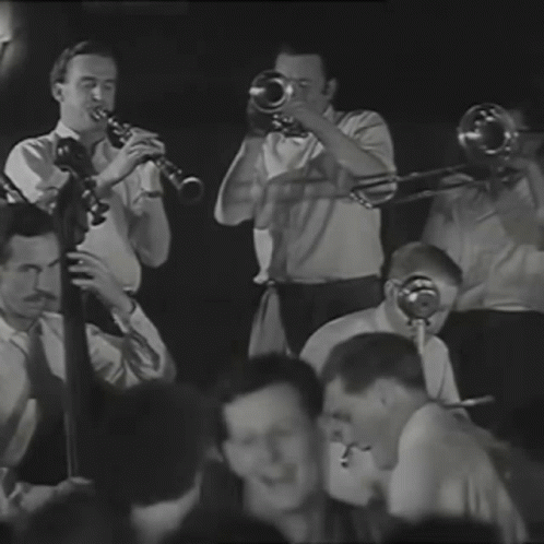 three men are playing trombones on stage while others look on