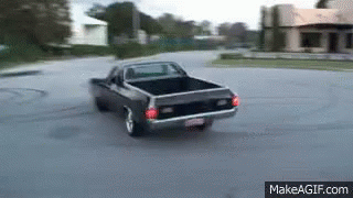 an old model muscle car drives down the street