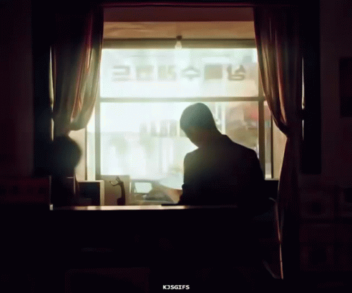 a man is sitting in front of a window looking at the television