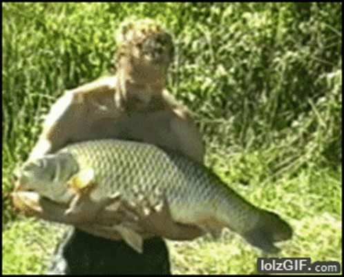 a man holding a fish in a grassy field