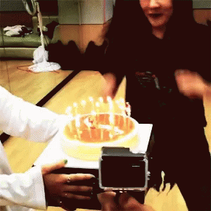 two men hold a video camera for a cake