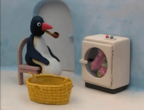 a penguin on a chair with a toy microwave and other toys