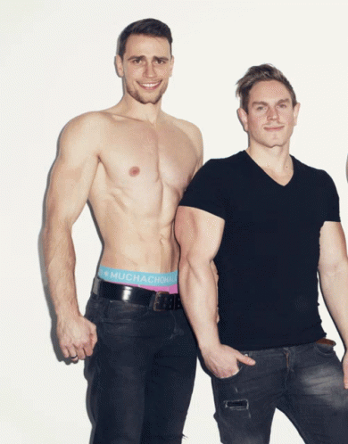 two men in tight jeans and shirts are posing