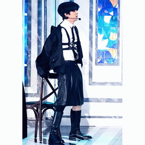a boy in a school uniform stands on a chair