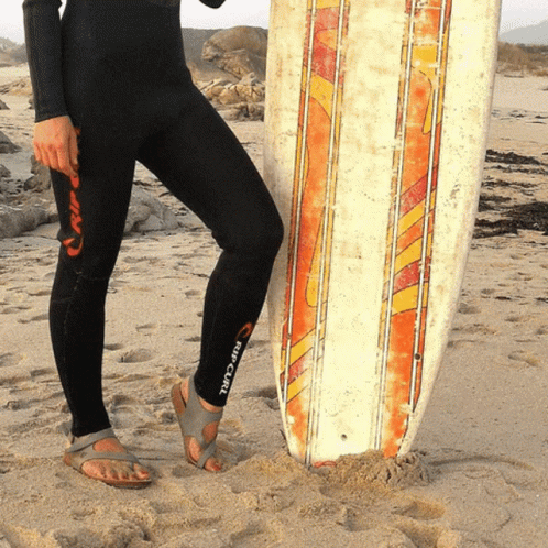 a woman in a black wetsuit holding a surfboard