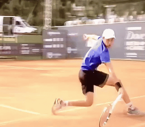 a young man lunges forward with a tennis racket