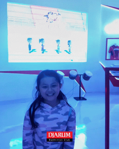 a girl is smiling at the camera while in front of a display case