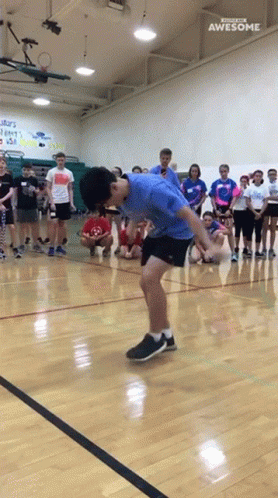 a boy kicking a ball on a gym floor