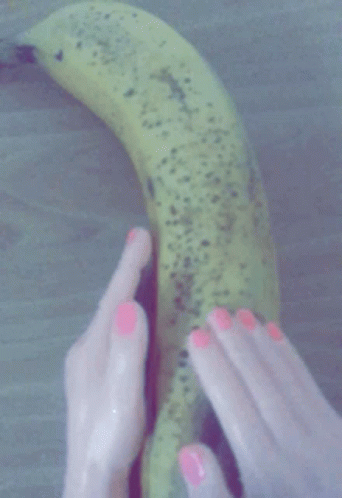 a woman's hand holding a green banana