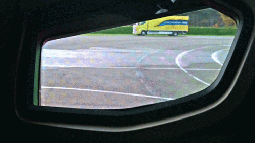 the inside of a plane window shows a blue bus on a runway