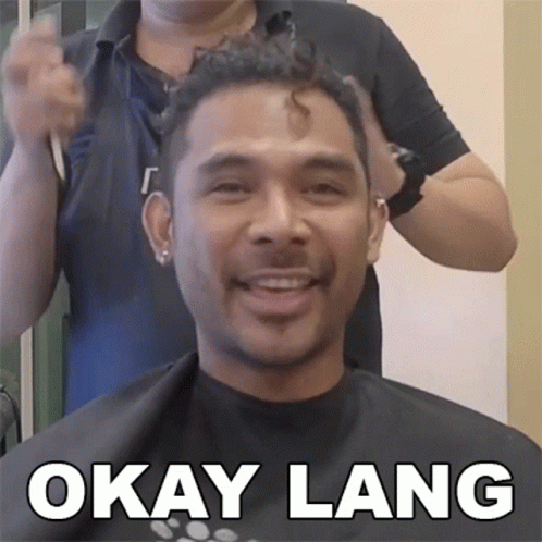 a man smiling while getting his hair cut