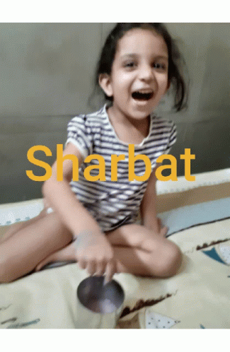 a young child sitting on a bed and smiling with the words sharat in front of her