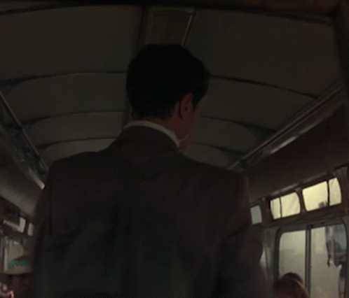 a man wearing a brown suit standing on a bus
