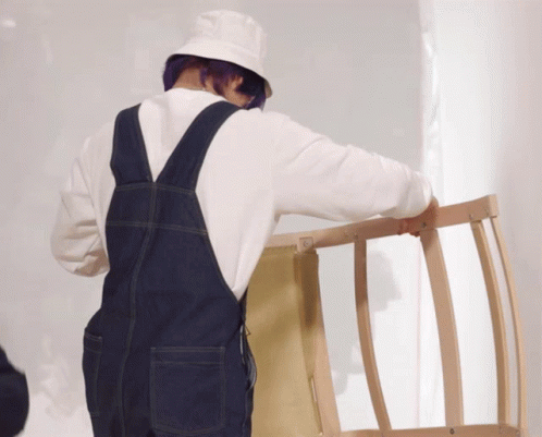 a man wearing brown overalls and a hat is holding a blue ladder